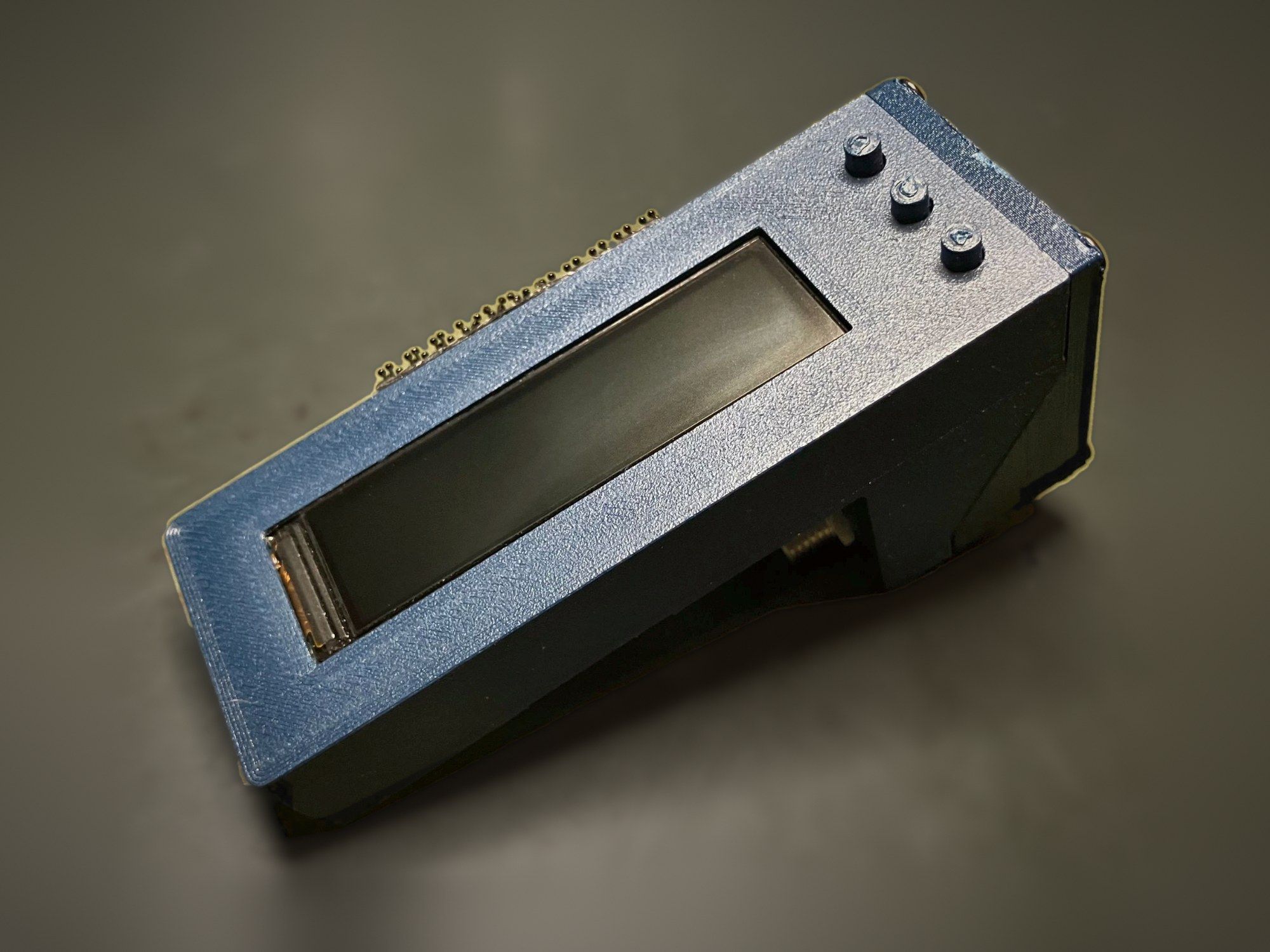 Agile v1.0 prototype in its blue 3D-printed enclosure, with the wide driver display and three buttons on the angled face